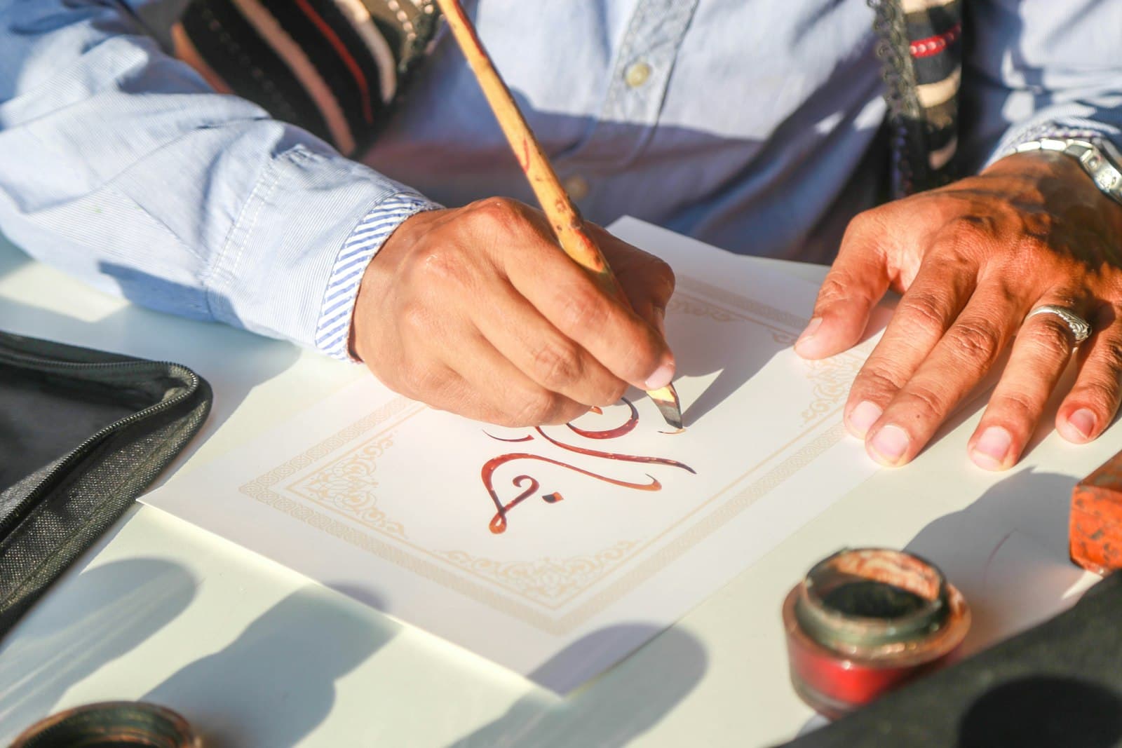 Tangan menulis khat Arab dengan pen di atas meja belajar